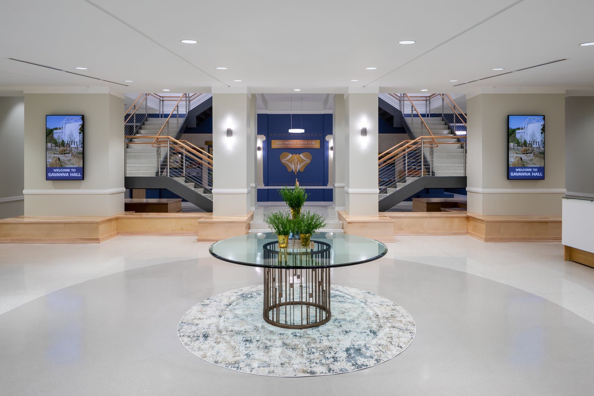 lobby with a table in the center of the room and a double-sided staircase leading to upper and lower levels