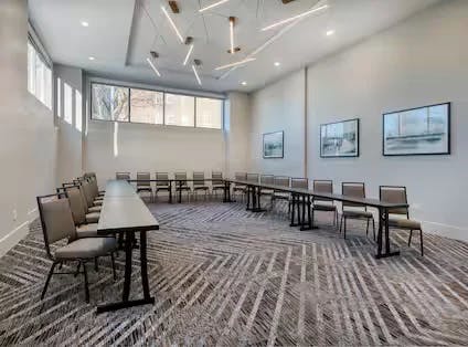 French boardroom with texture lined carpet, long tables and chairs. Room has white walls, windows along the top of two walls and bar lights hanging from the middle of the room.