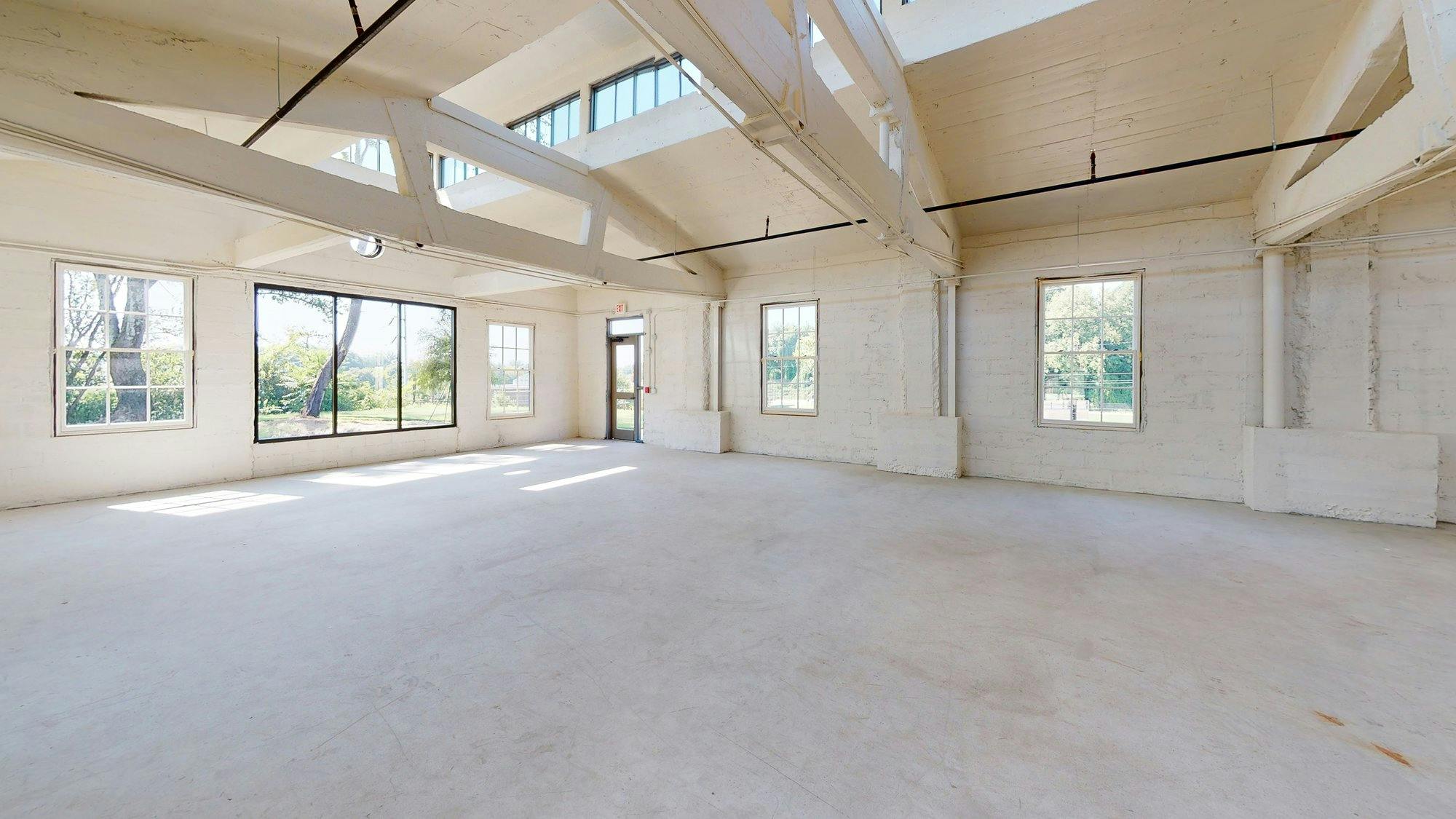 An empty room with white walls and large windows.