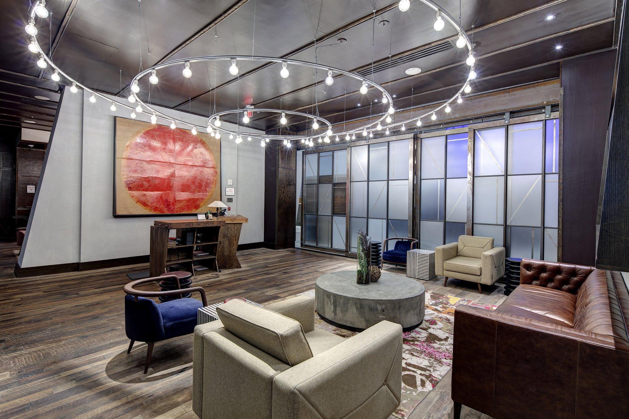 Large circular light fixture hangs from the ceiling of an industrial seating area.