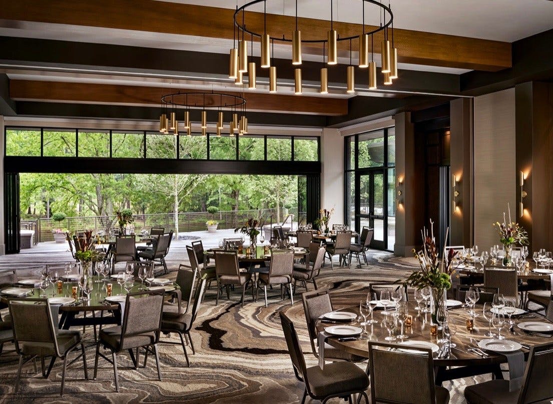 Hotel dining room with ornate fixtures and wide opening to an open air space surrounded by lush greenery.