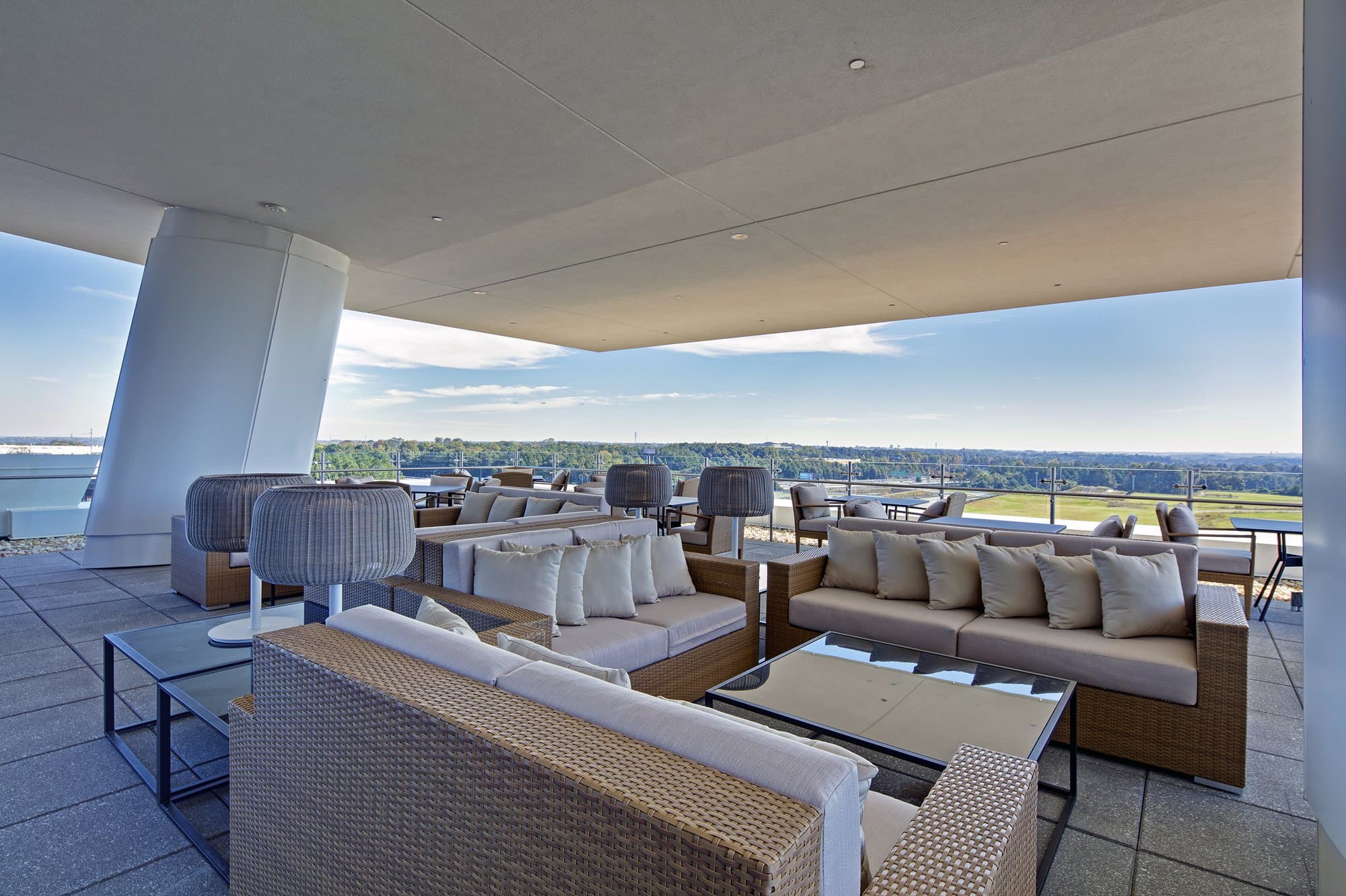 Covered rooftop terrace with comfortable cushioned seating overlooking the greenery of Atlanta. 