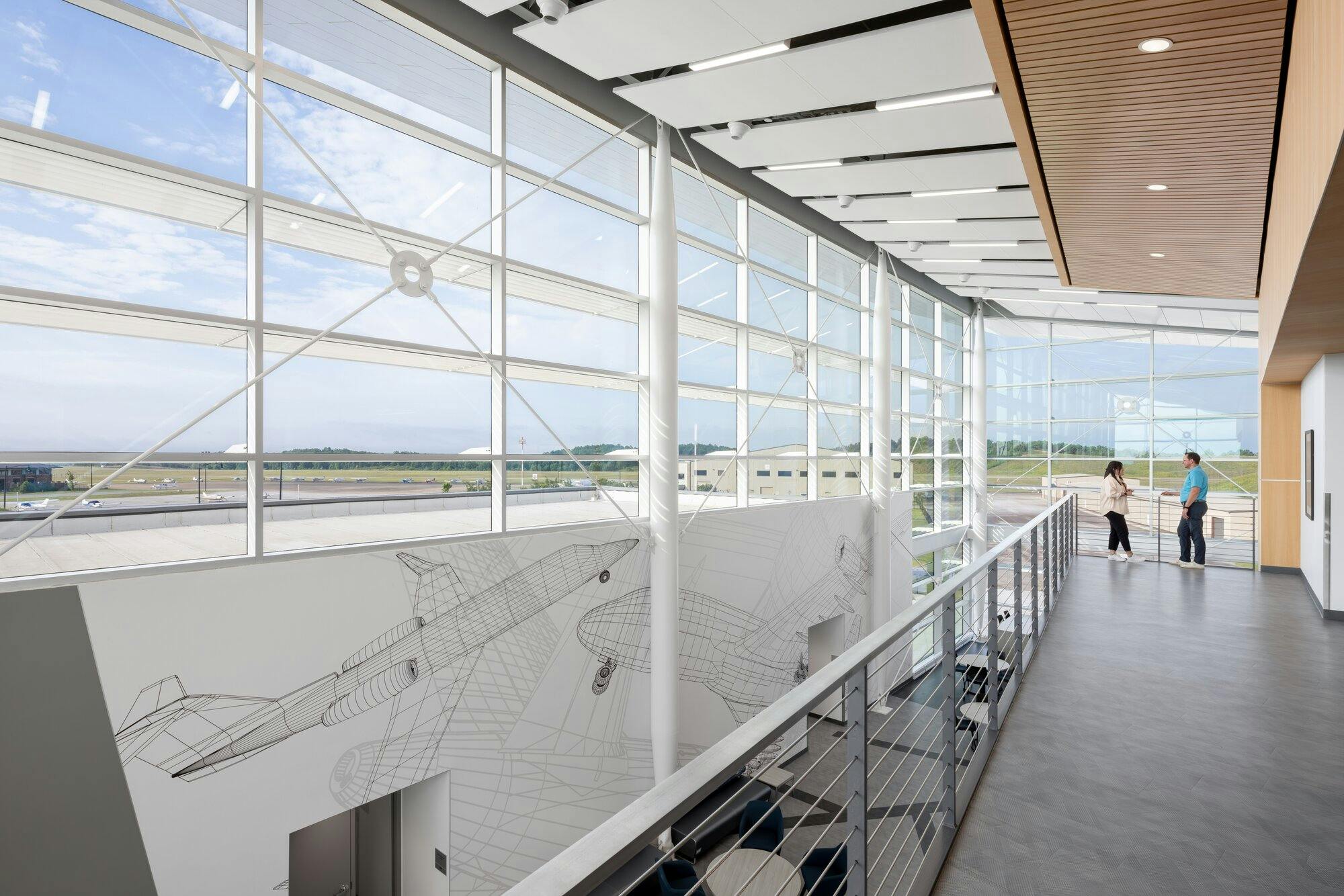 Second floor view surrounded by windows, wood beam ceiling with recessed lighting, and a walkway.