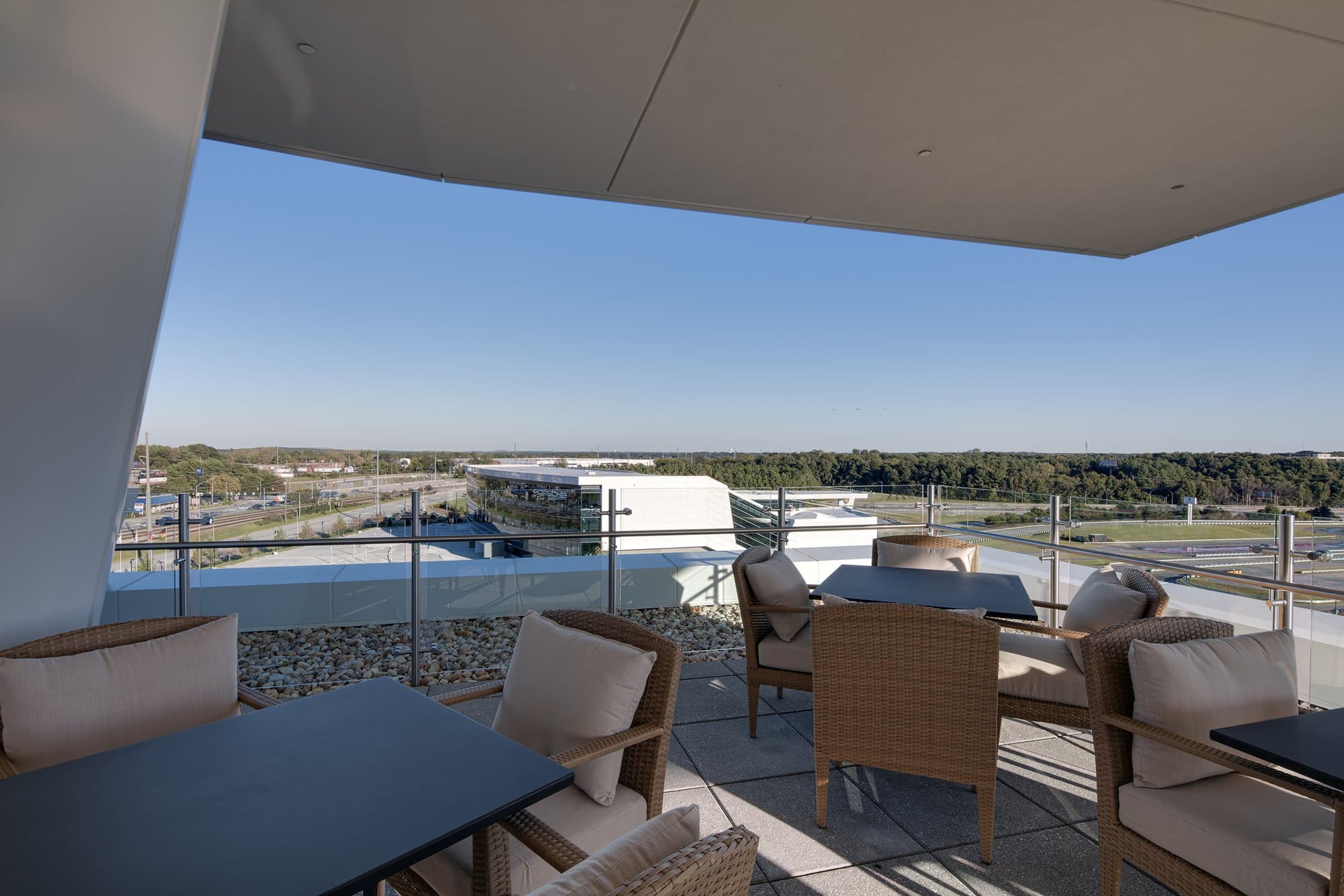 Covered rooftop terrace with multiple tables overlooking the a race track.