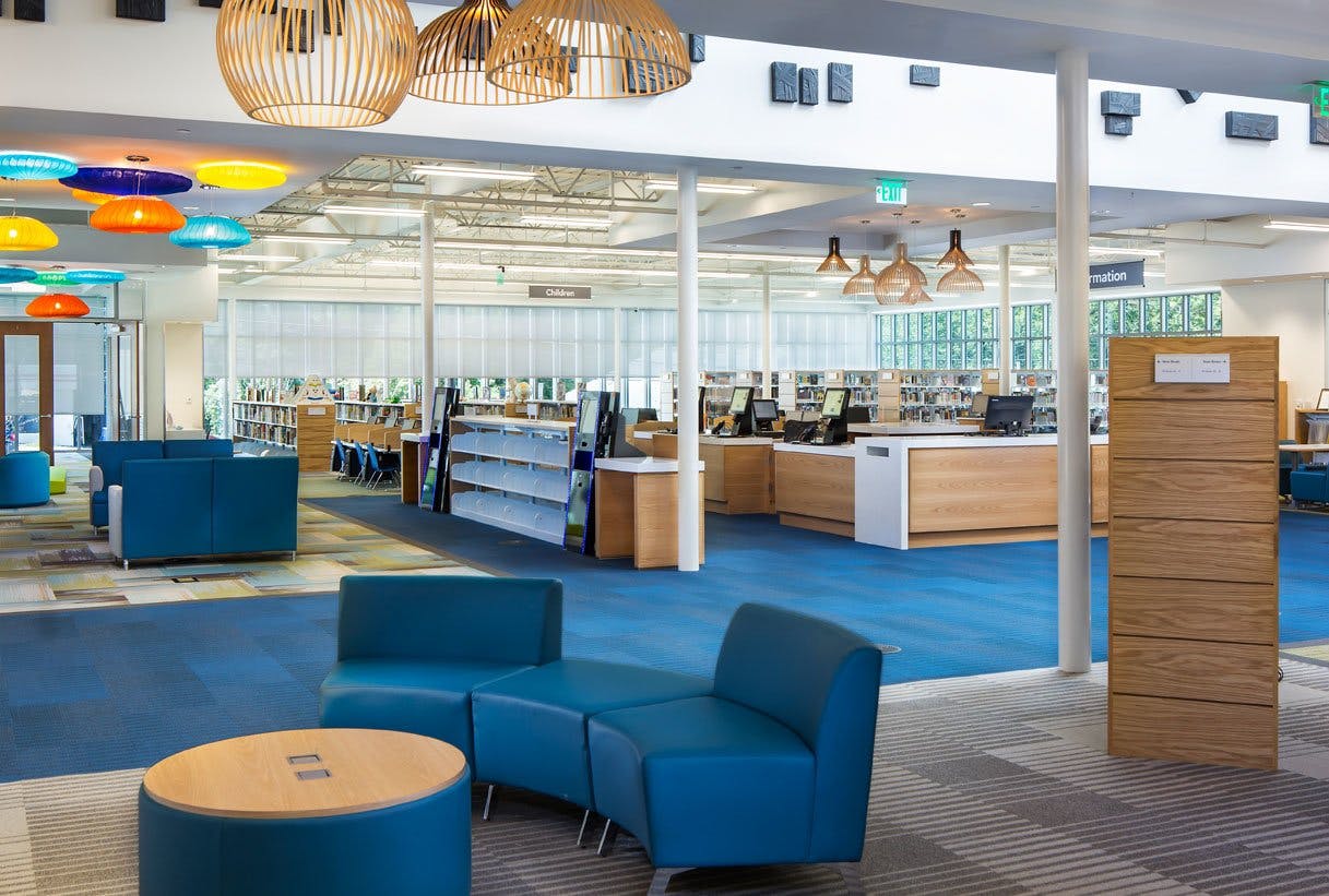 Library interior with seating areas, lighting, and books.