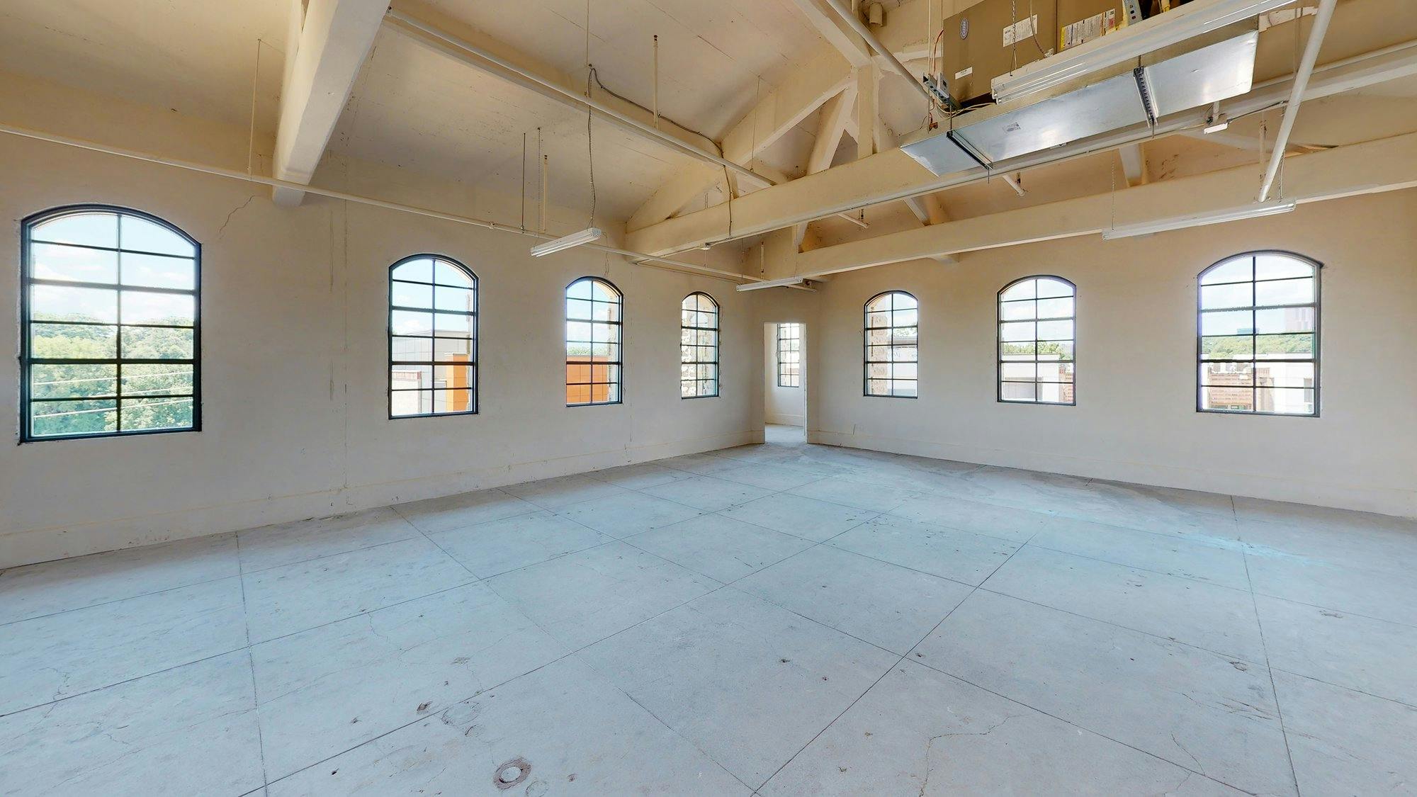 An empty room with large windows and arches.