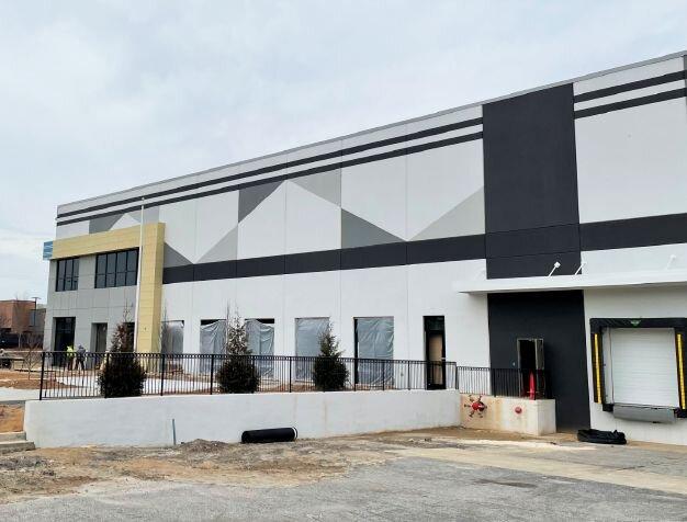 Exterior image of the building  with large windows, flagpole, and landscaping.