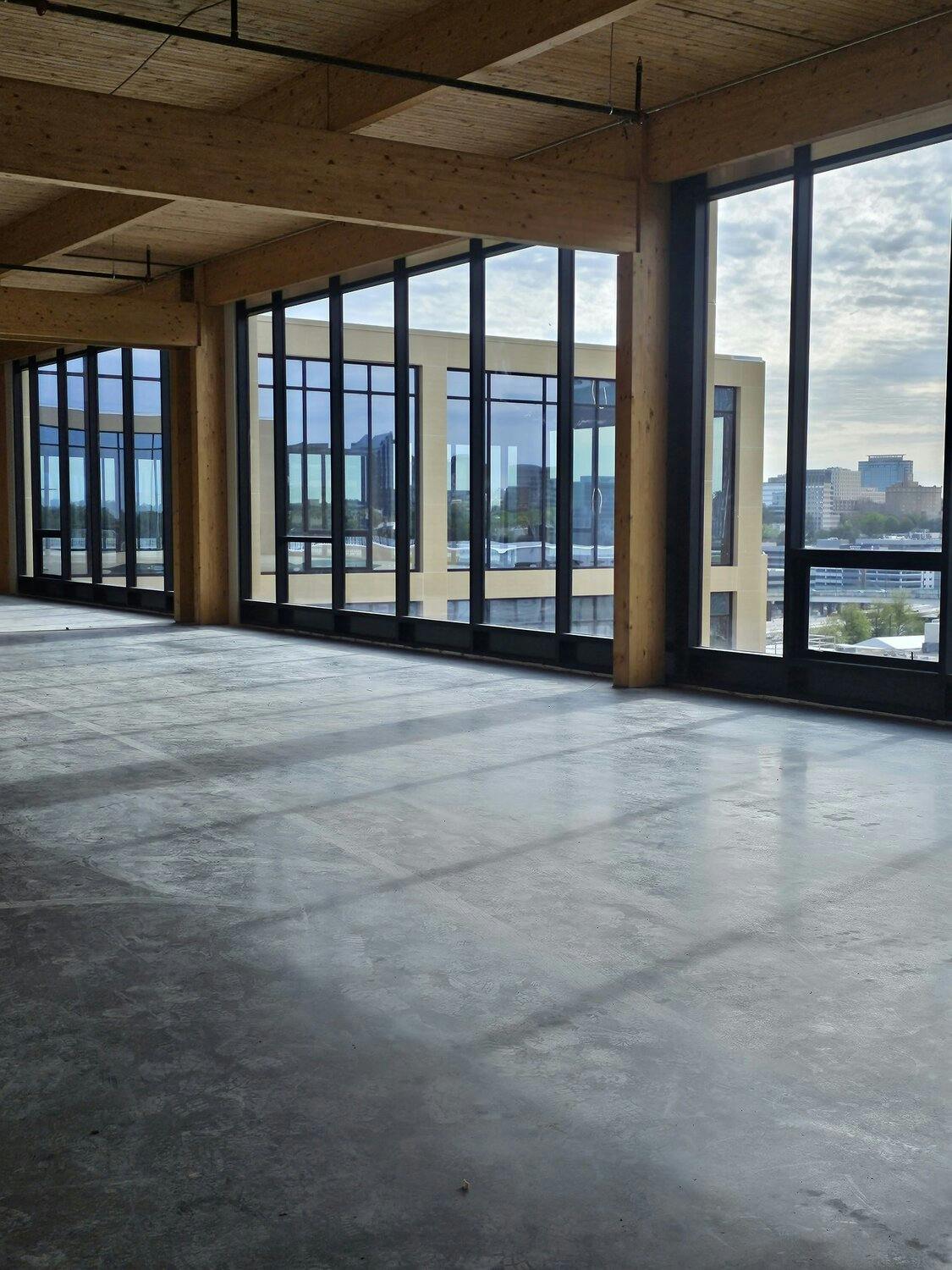 Level 3 of building with concrete floor, timber beams and windows overlooking opposite side of building.