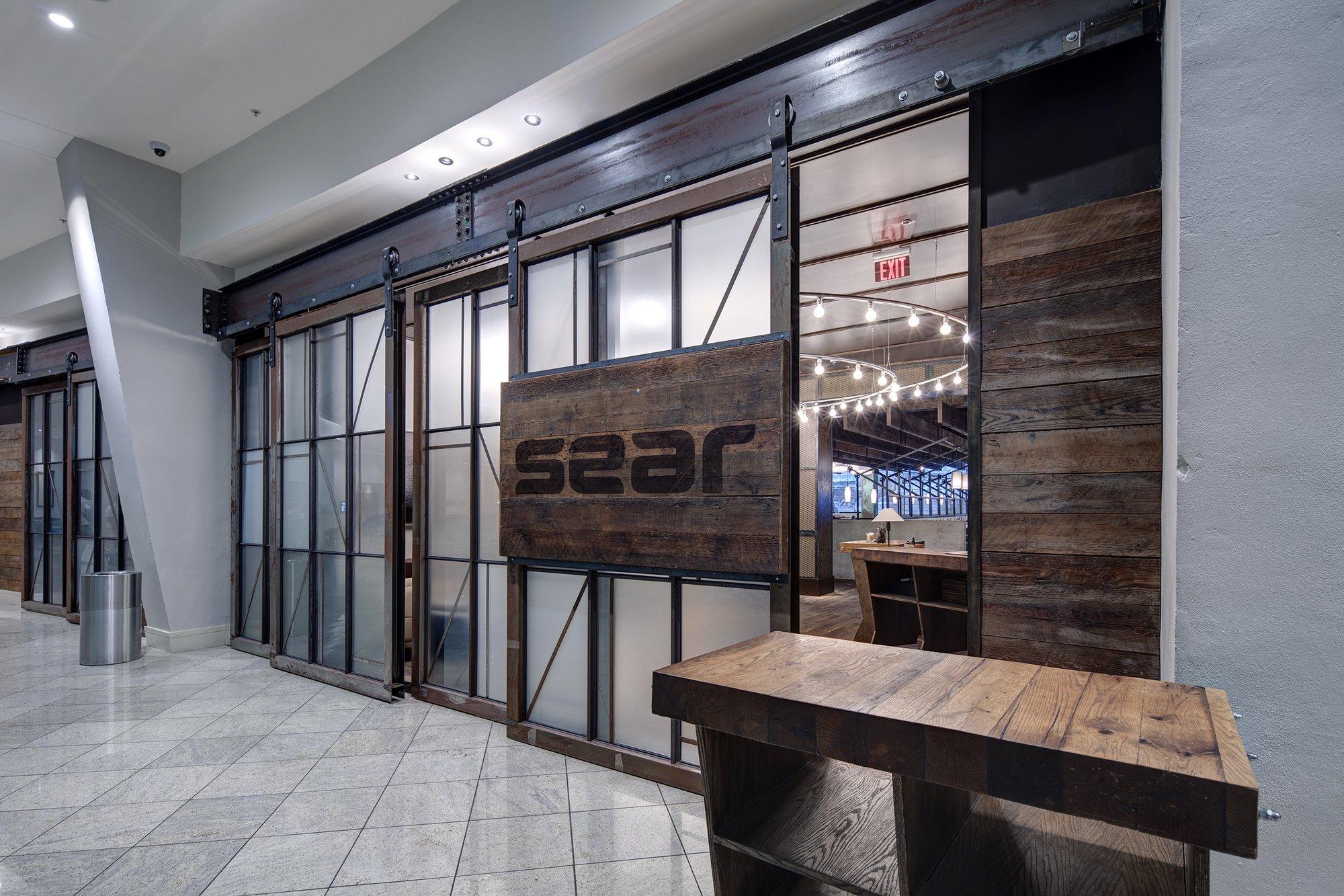 "sear" is etched into a large wooden sign next to a restaurant entrance.