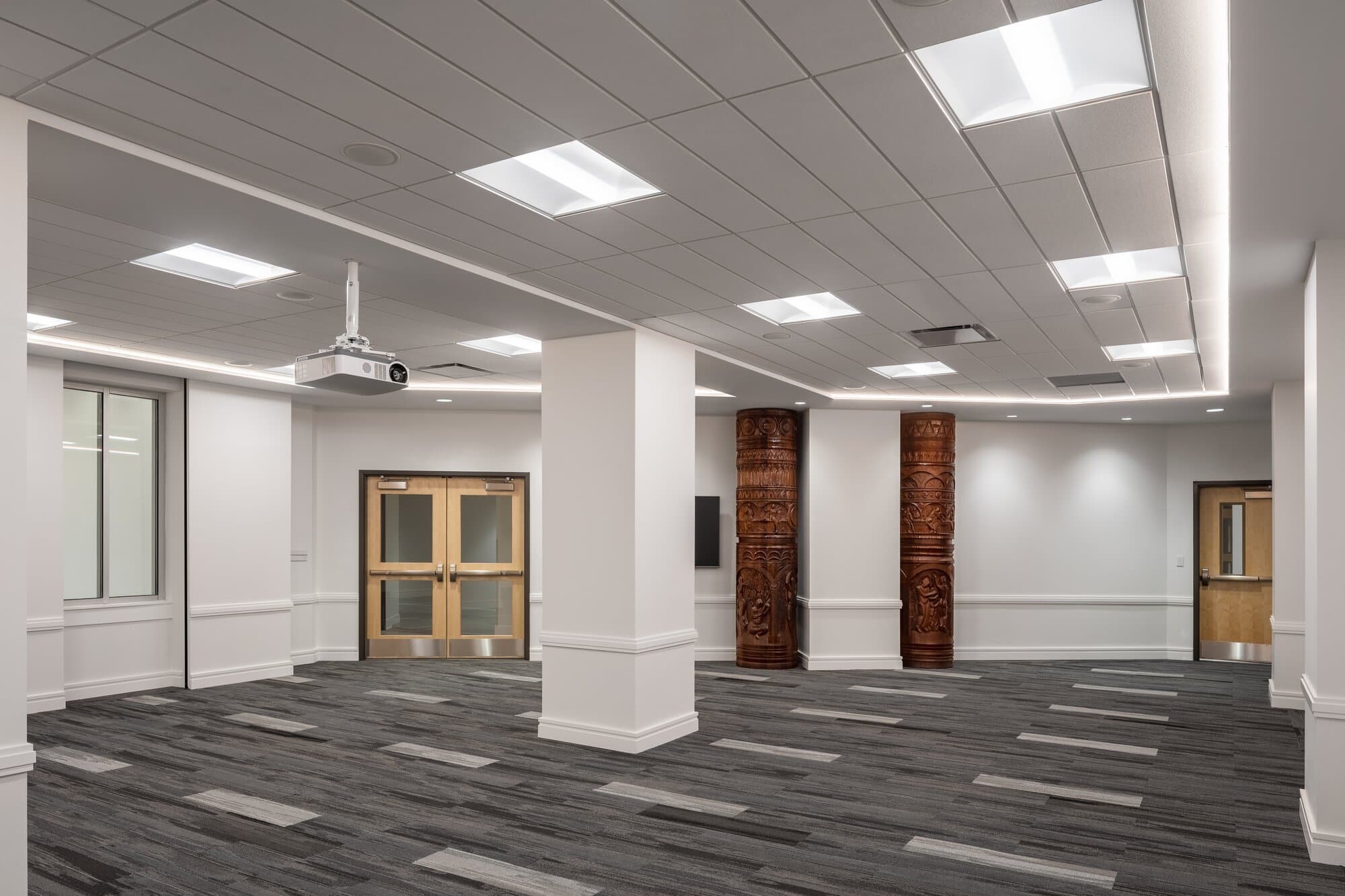 Large presentation space with exposed brick walls, columns, new paint, flooring, and an overhead projector