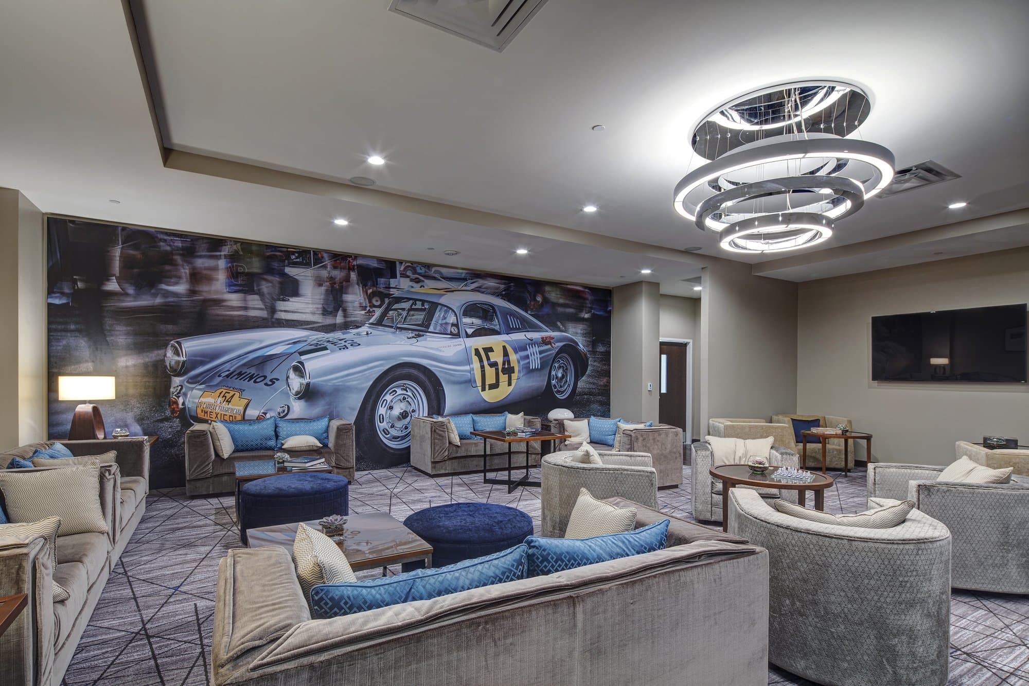 Hotel lounge area with modern lighting and plush seating. A mural of a classic Porsche is seen on the back wall.