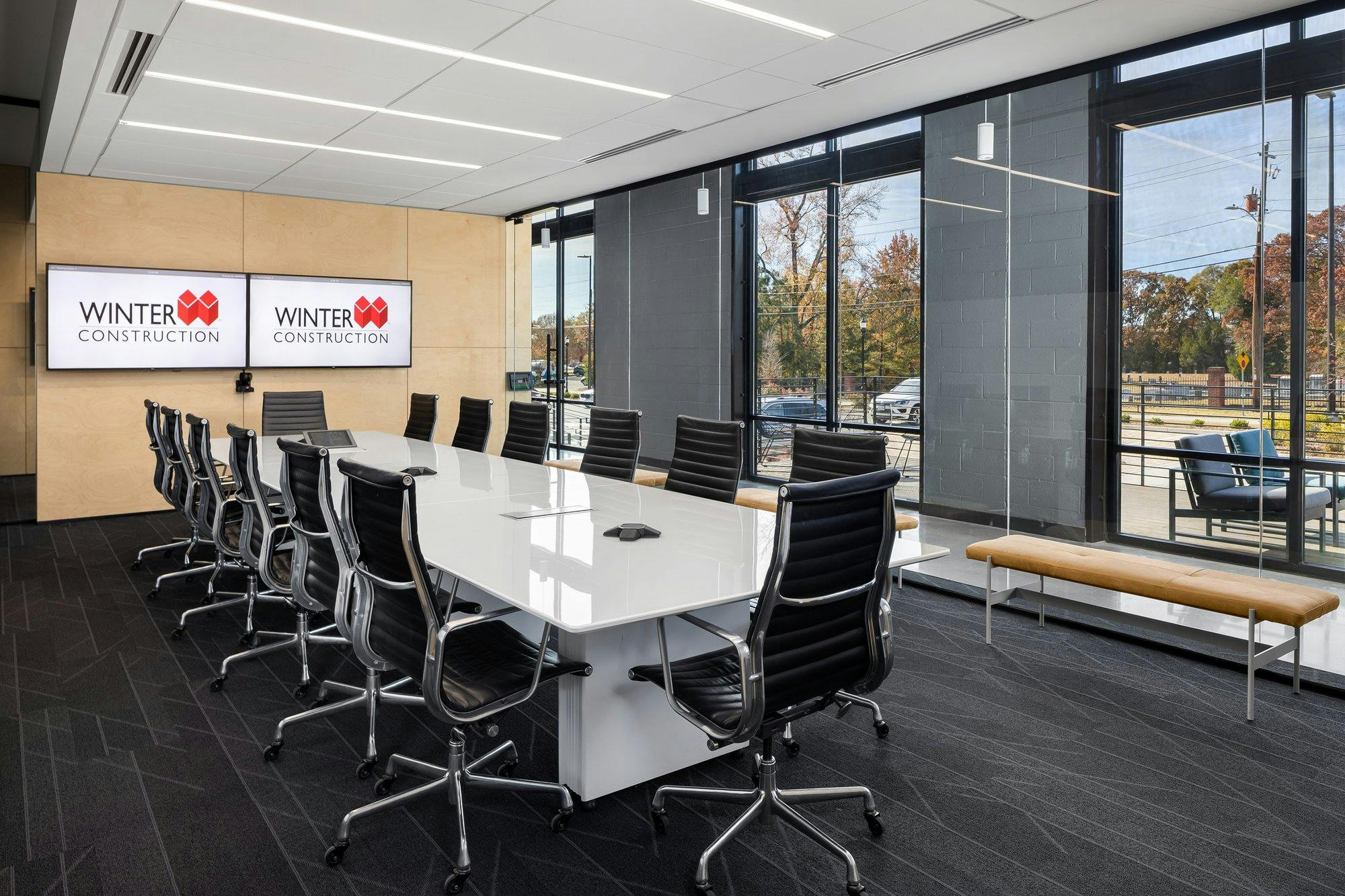 Conference room with fourteen chairs around conference table and TVs on the wall