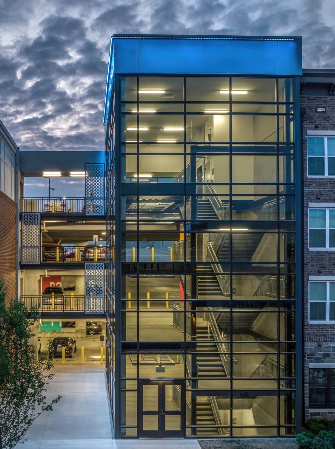 Outside view of stairwell inside of parking garage with glass windows from top to bottom of structure. Full glass view.