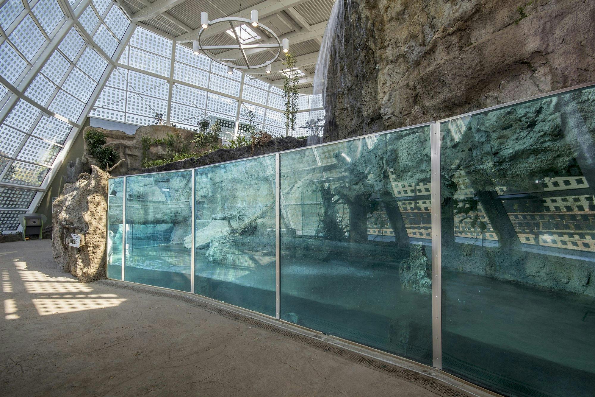 Interior of a reptile exhibit with a barrier in the foreground and a reptile habitat in the background