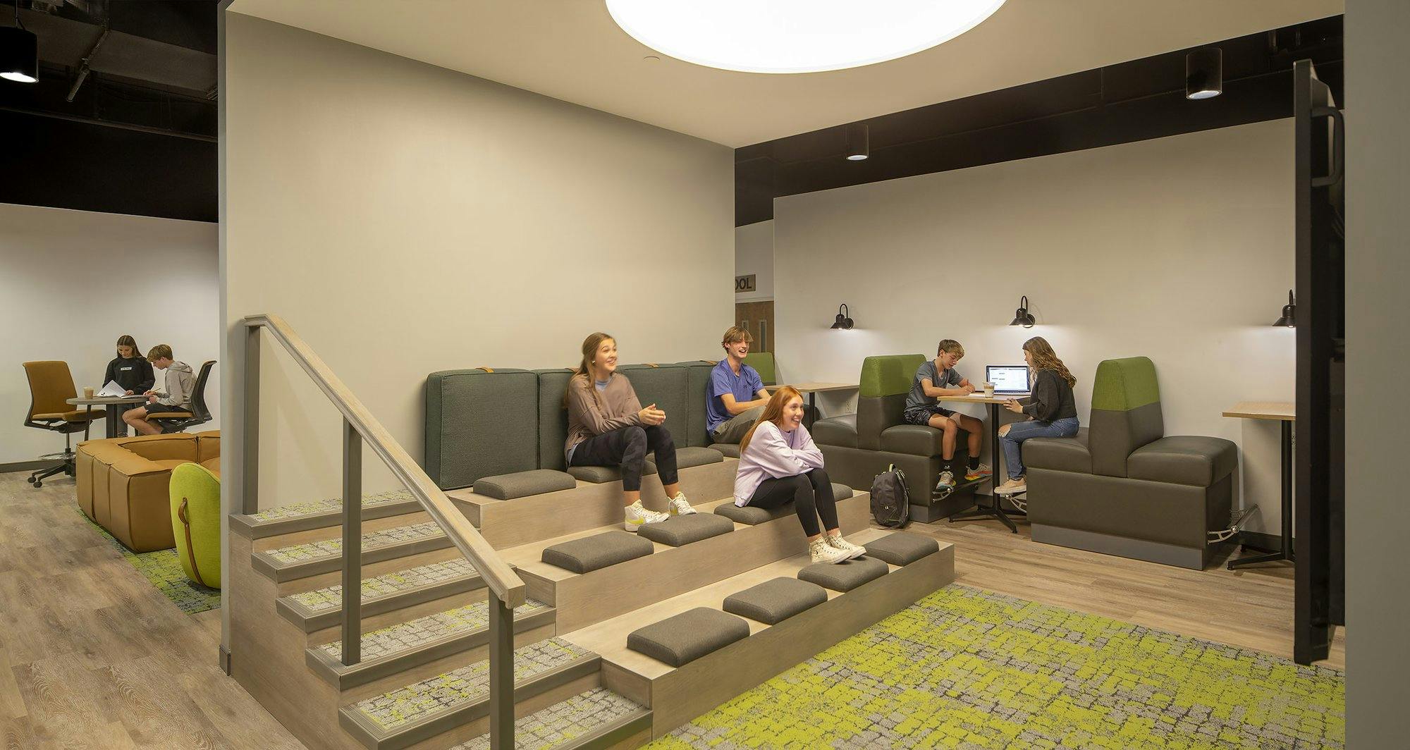 cozy meeting space for church youth, featuring  padded steps for seating and booths for students to socialize, eat, and work in