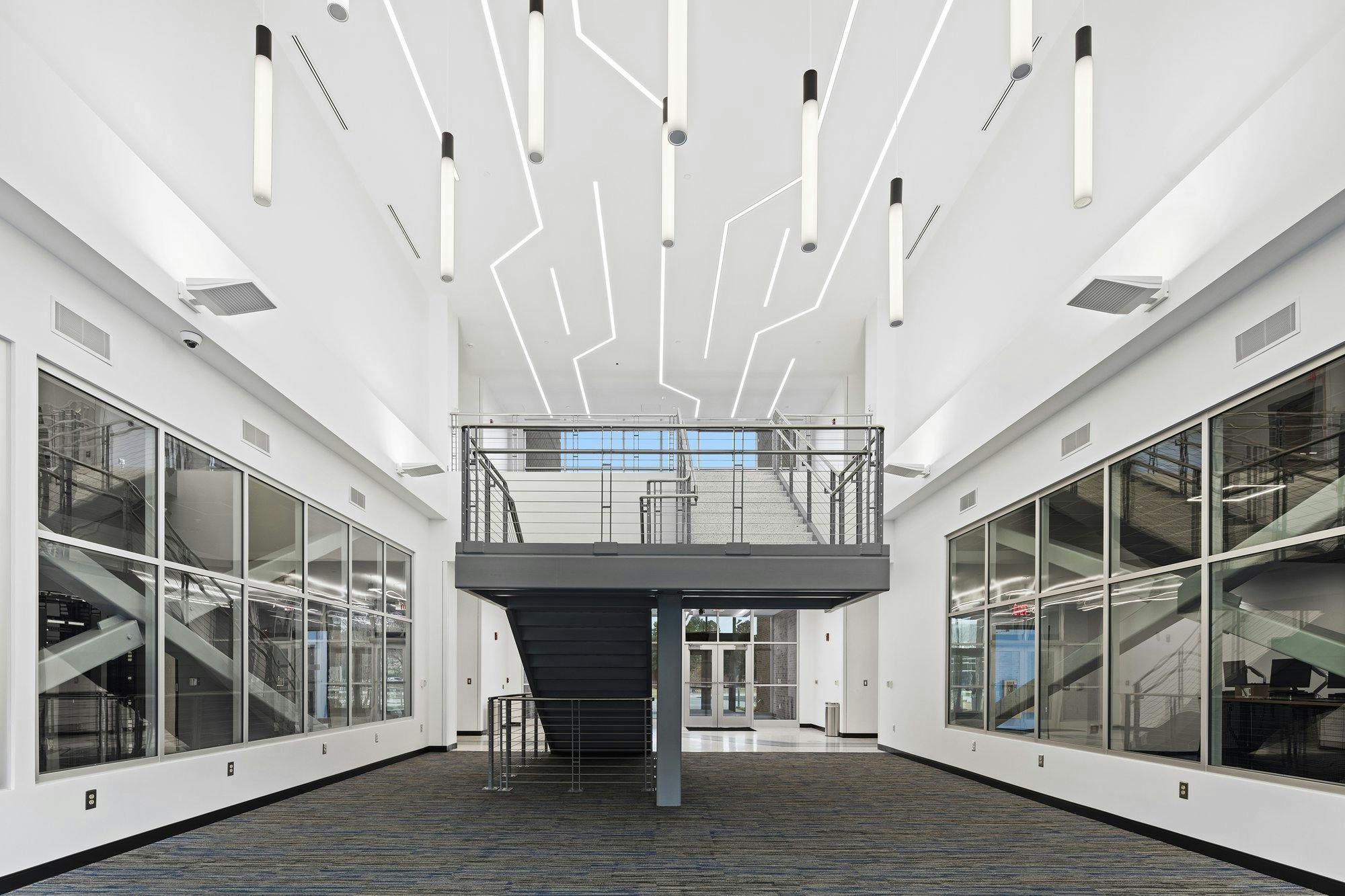 Stairwell with lights hanging from ceiling and windows on both sides.