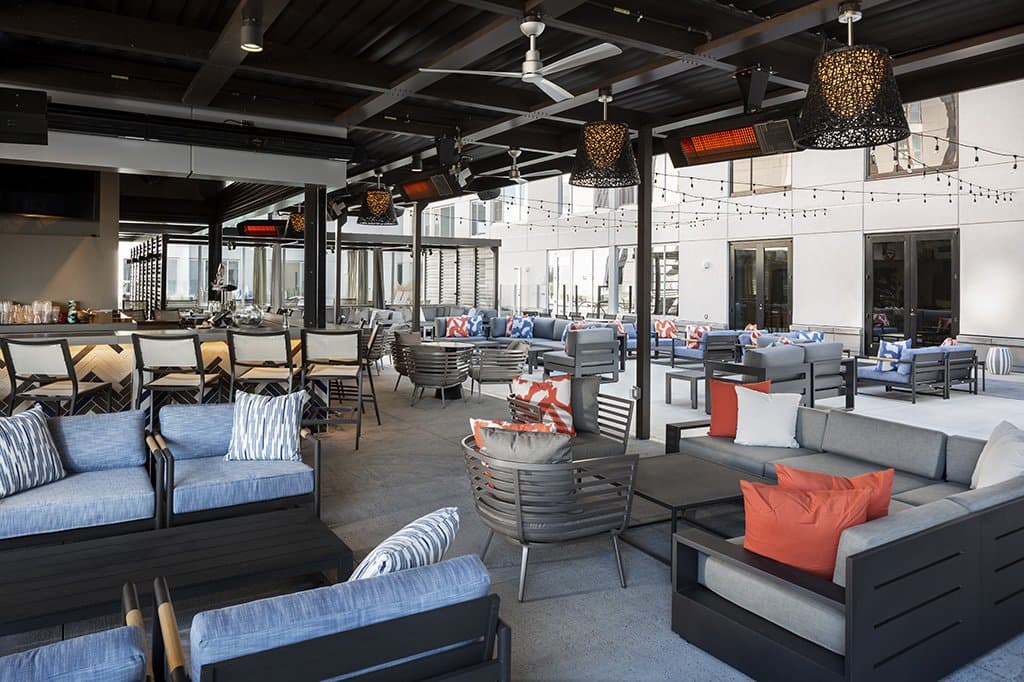 Covered outdoor rooftop dining area with many cushioned seats.