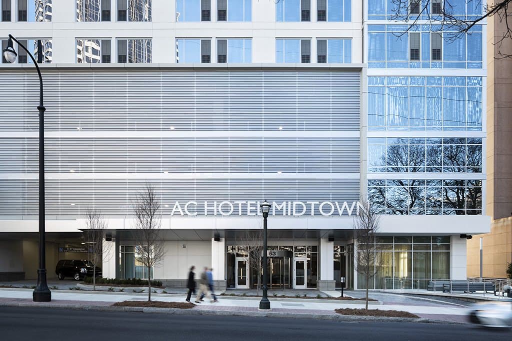 A sign reads "AC HOTEL MIDTOWN" over a busy city street.