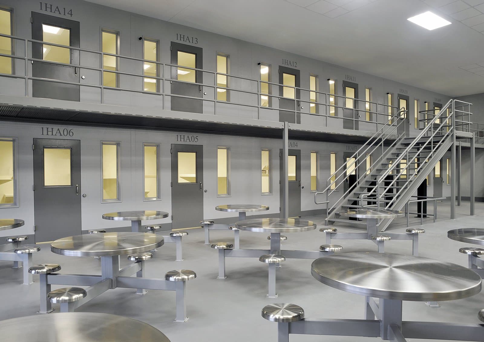 Open detention center common area with metal tables and chairs.