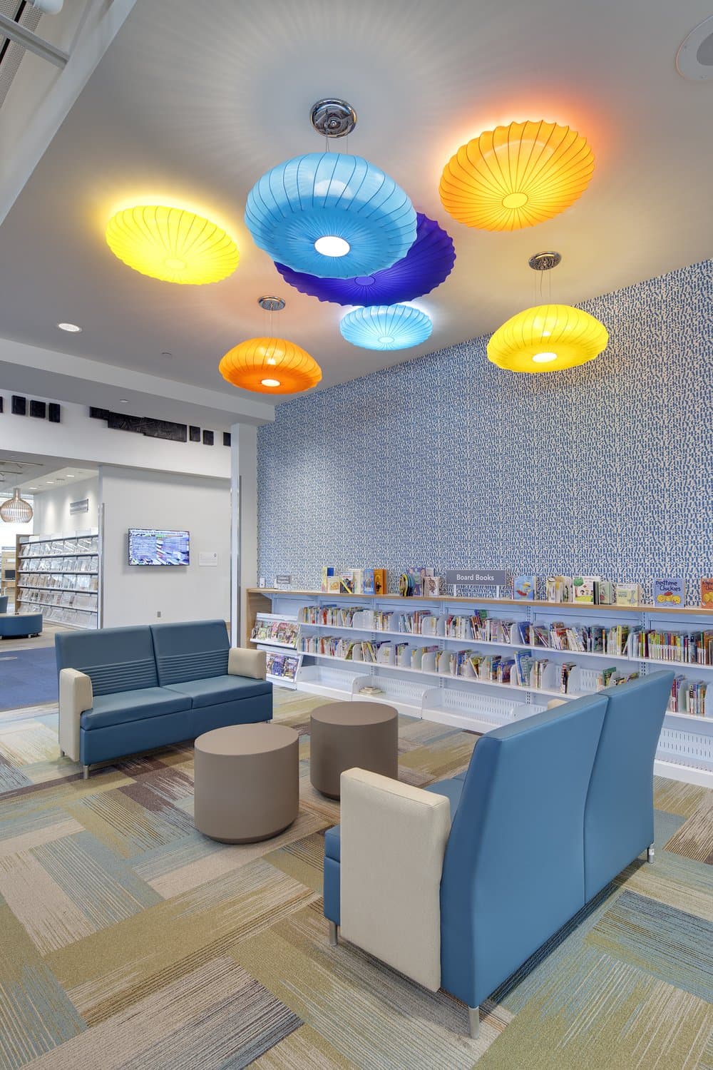 Library searing area with sofas and a wall of books on shelves.