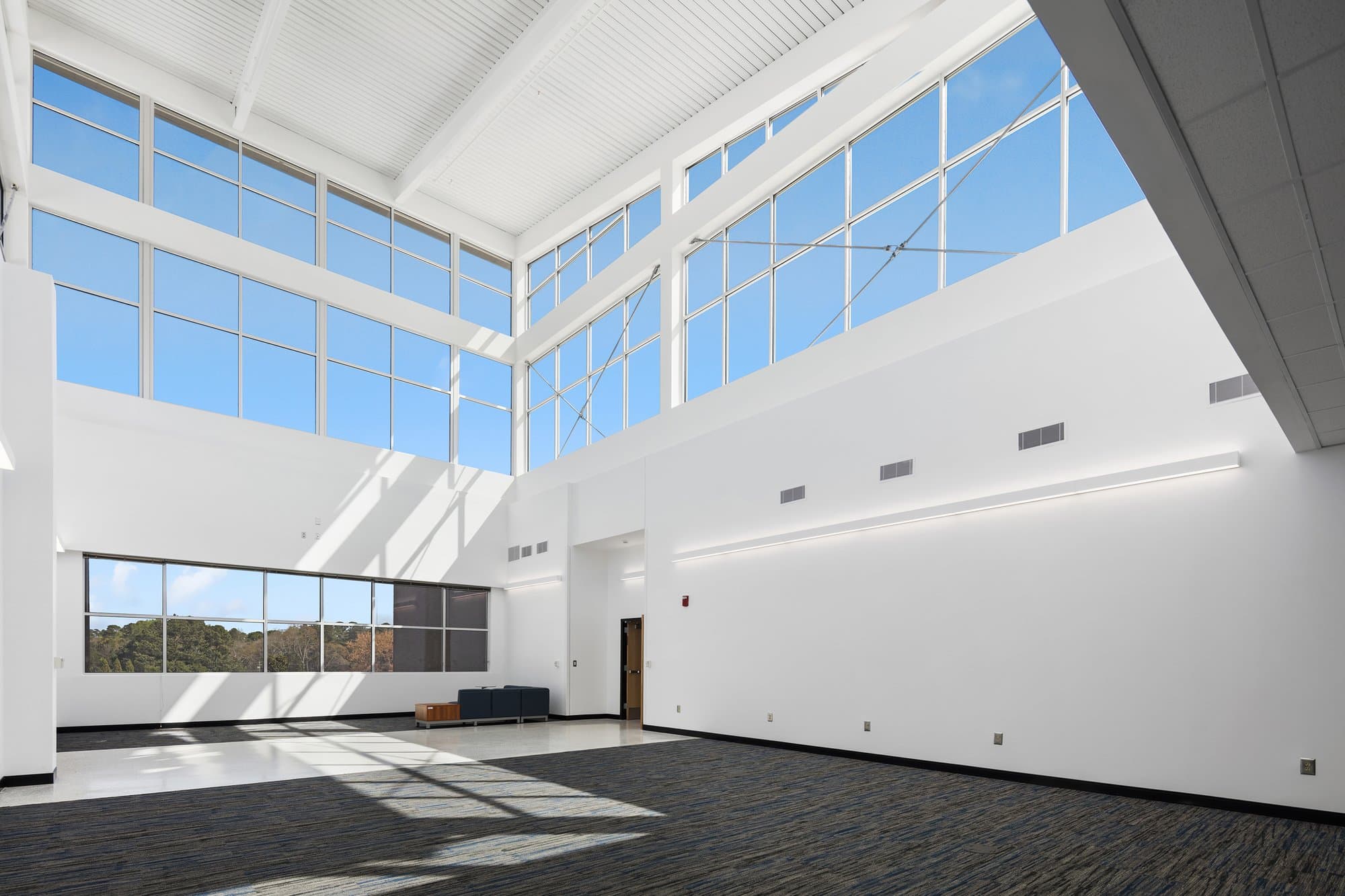 Large industrial sized room with white walls and big windows across the top.