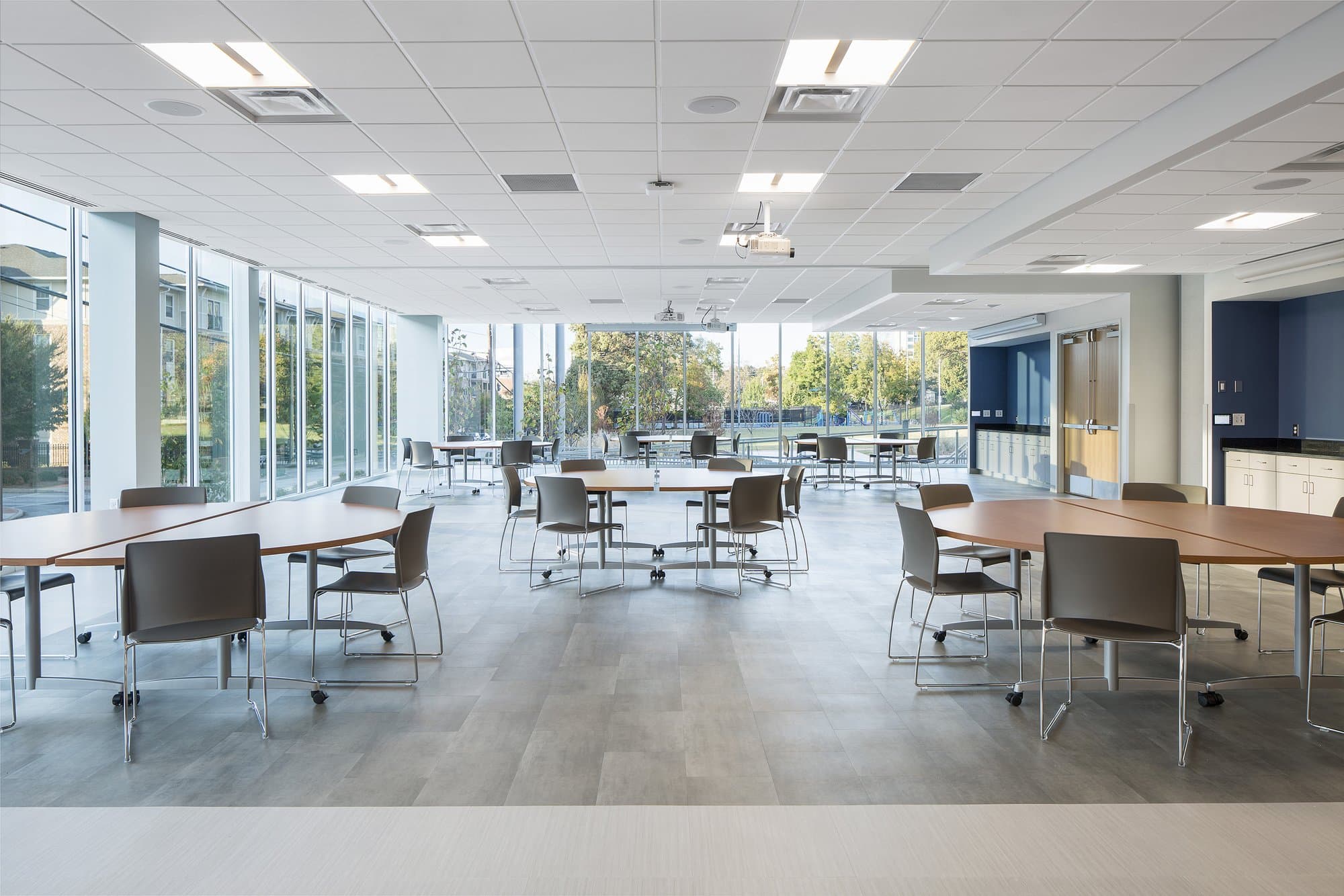 large open room with lots of windows, large circular tables, and chairs