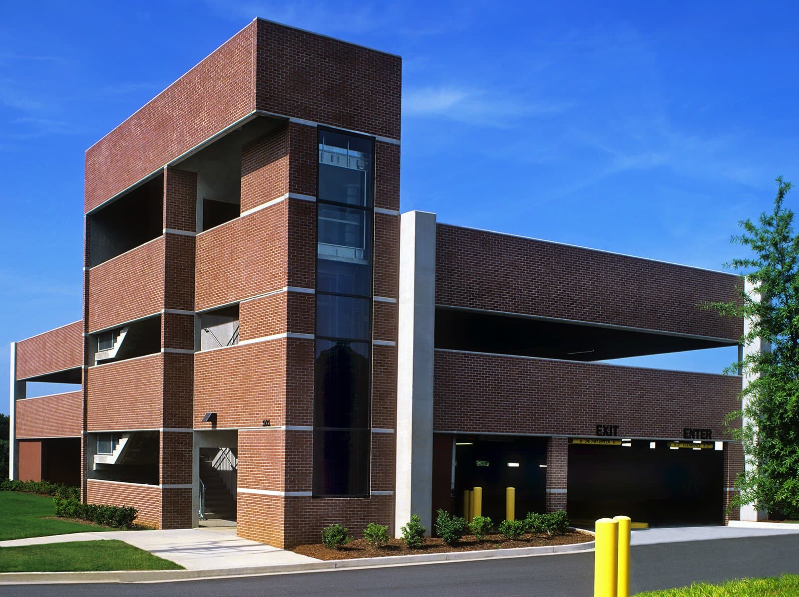 Side view of parking garage with elevators and sidewalks.