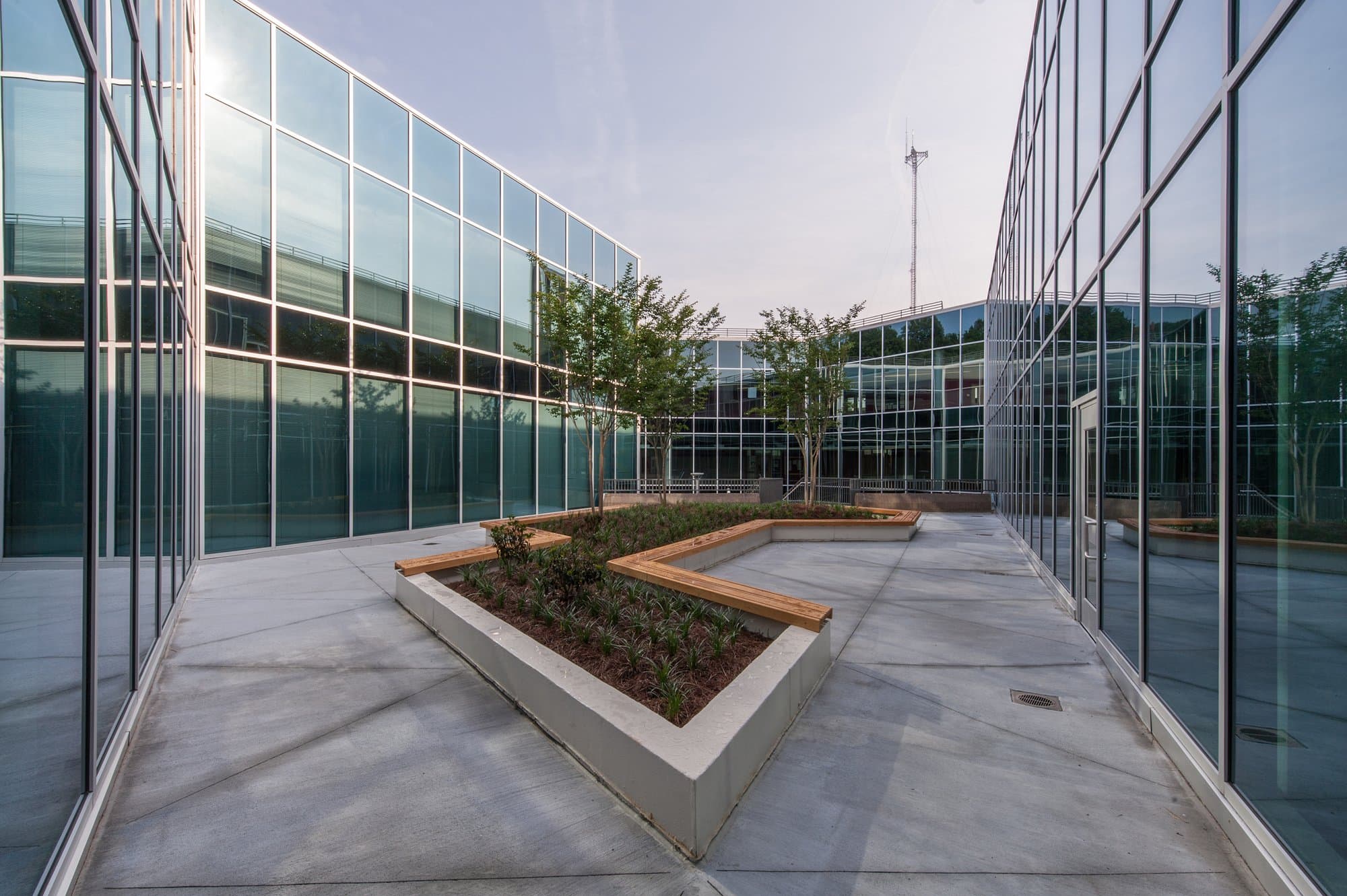 Geometric raised planter with seating surrounded by two stories of glass windows.