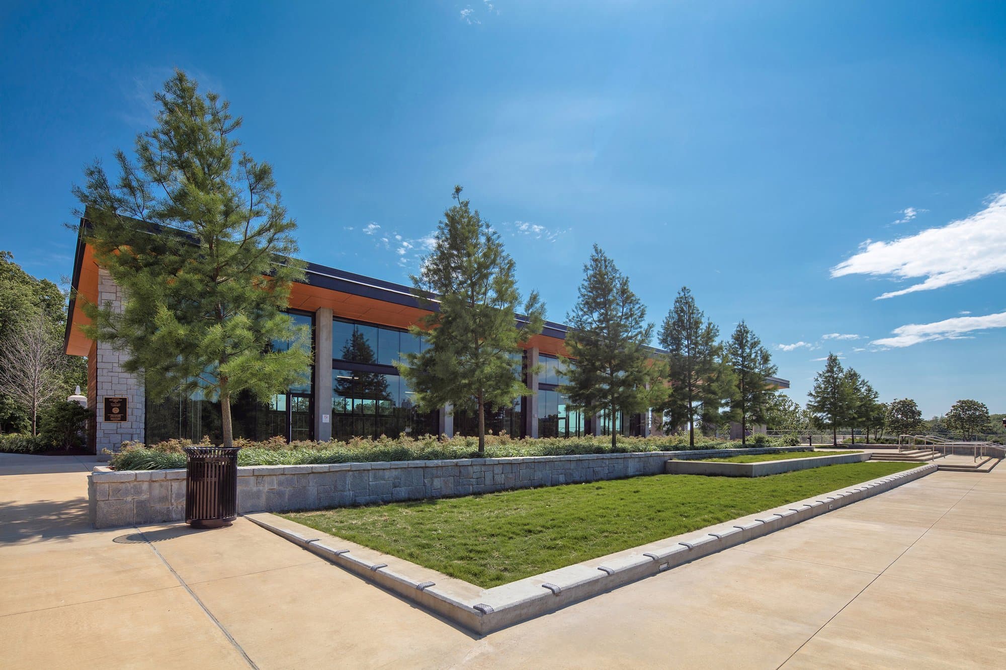 Side view of parking garage with grassy area, trees, and sidewalks.