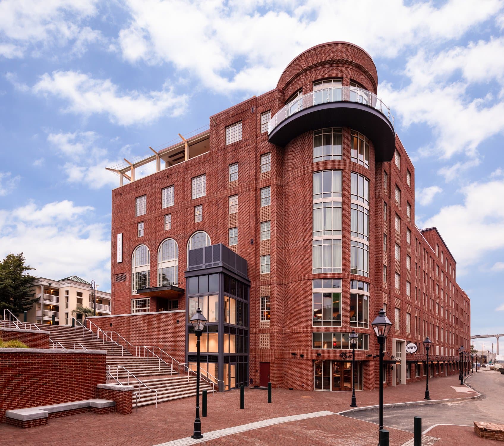 A rounded corner of a tall brick building with many windows.