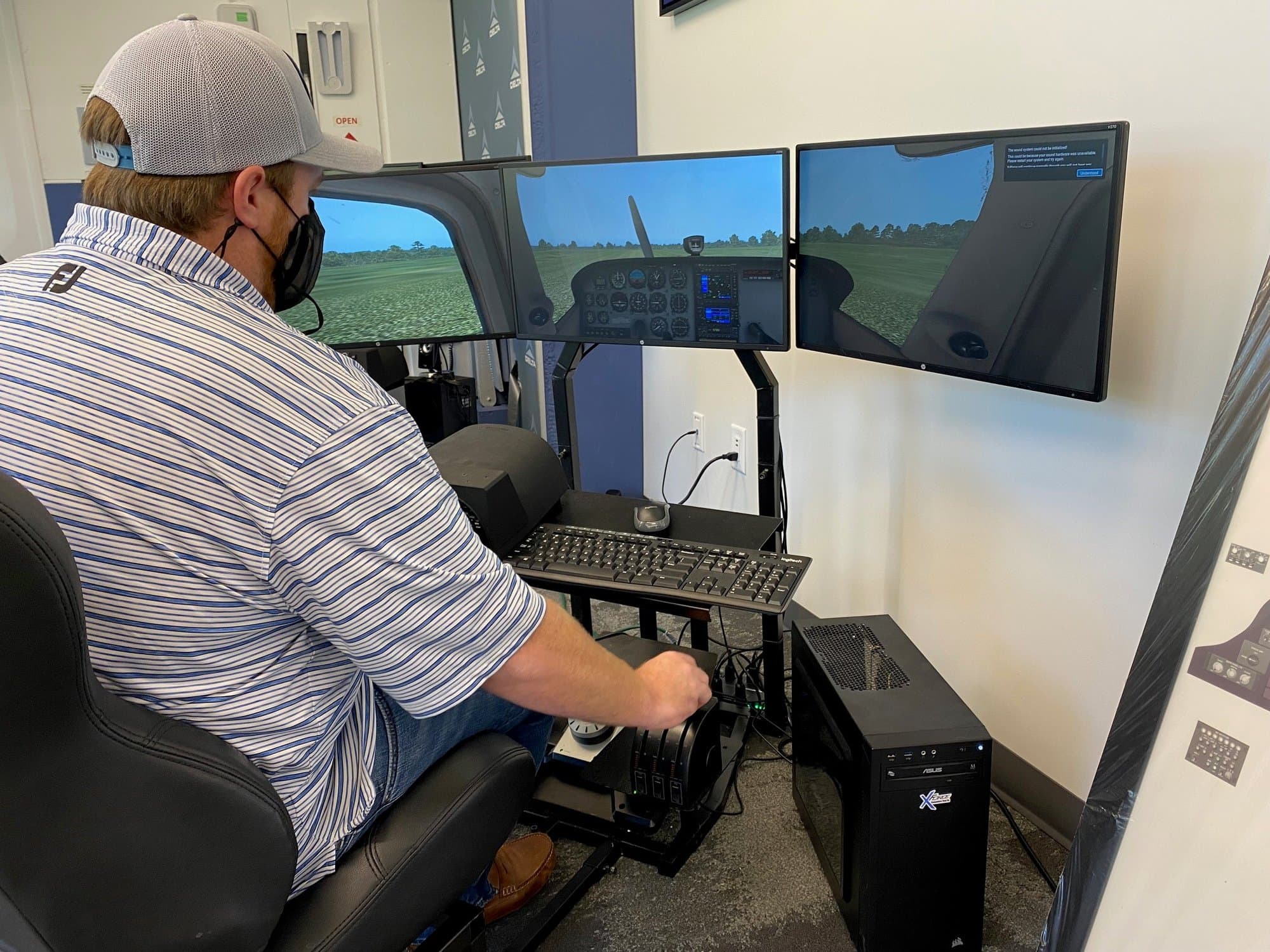 Gentleman in polo shirt and hat holds the throttle of a flight simulator.
